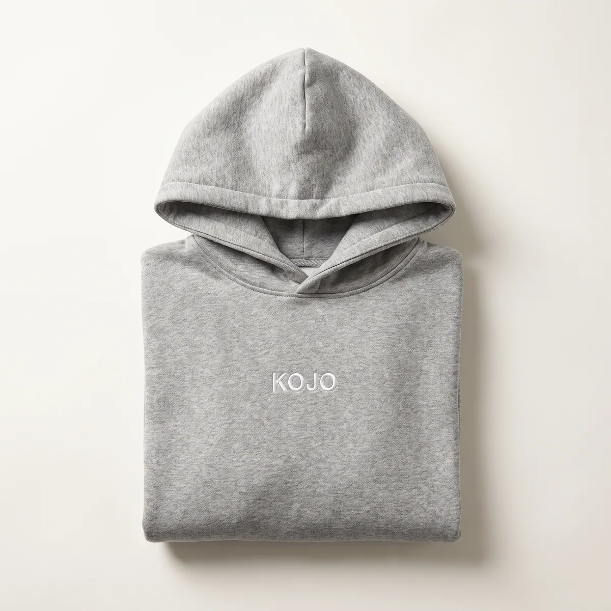 Folded heather grey hoodie with small white KOJO embroidery at the chest